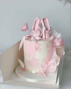 a pink cake with ballet shoes on top and flowers in the middle, sitting on a white plate