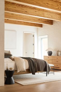 a bedroom with white walls and wood floors, along with a bed that has a blanket on top of it