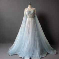 Transform your wedding day into a fairytale with the Light Blue Beaded Long Sleeve Bridal Gown. This elegant tulle wedding dress is adorned with exquisite beadwork that shimmers with every step, creating a magical and enchanting look. The long sleeves and high neckline offer timeless sophistication, while the intricate beading adds a touch of luxurious detail. The fitted bodice flows into a voluminous tulle skirt, giving you an ethereal silhouette that is both dreamy and romantic. A charming bow at the back adds a whimsical and elegant touch, making this gown truly unique. Perfect for the bride who seeks a blend of elegance and enchantment, this gown ensures a flattering fit that highlights your curves and provides all-day comfort. Embrace the beauty and magic of this light blue beaded bri Ice Blue Wedding Dress Bridal, Ethereal Gown Fairytale, Baby Blue Wedding Dress, Ice Blue Gown, Light Blue Wedding Dress, Sleeve Bridal Gown, Wedding Dress With Bow, Simple Satin Wedding Dress, Blue Wedding Gowns