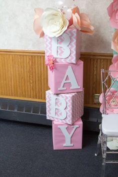 pink and white baby blocks stacked on top of each other in front of a chair