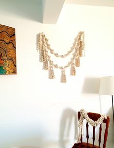 a room with a chair, lamp and pictures on the wall above it that is decorated with tassels