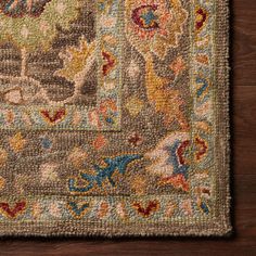 a close up of a rug on a wooden floor with an animal and flower design