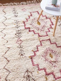 a white rug with red and gold designs on the floor next to a coffee table