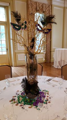 there is a vase with feathers on the table in front of some wine glasses and place settings