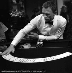 a man in a bow tie leaning over a black table with white writing on it