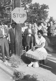 black and white photograph of a woman sitting on a bench next to a stop sign