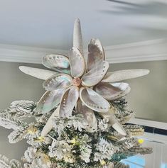 a white christmas tree decorated with flowers and seashells in the shape of a flower