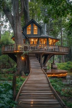 a tree house in the woods with lights on it's deck and stairs leading up to