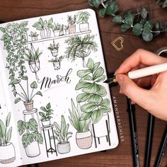 a person is holding a pen and looking at a notebook with plants on the pages