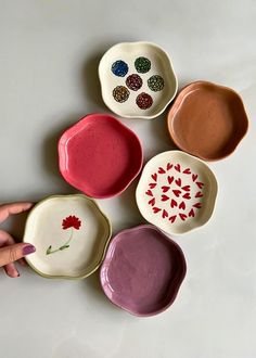 four bowls with different designs on them are being held by a person's hand