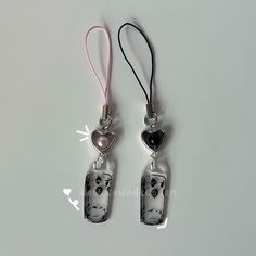 two silver earrings with black and white designs on them, one has a heart hanging from it's side