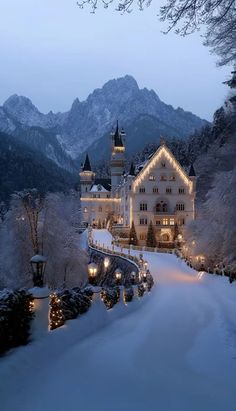 a large white building with lights on it's side in the middle of snow