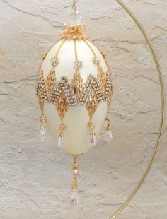 an ornament hanging from a gold hoop on a white wall with crystal beads