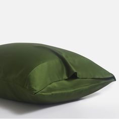 a green pillow on a white surface with the cover pulled back to reveal it's inner corner