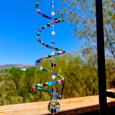 a wind chime with beads hanging from it's side on a wooden deck