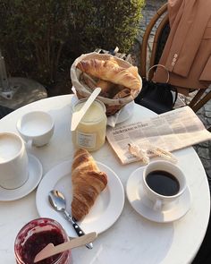 croissants, butter and jam are sitting on a table with coffee in front of them