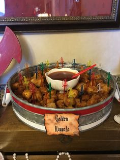 a bowl filled with tater tots sitting on top of a table next to a sign