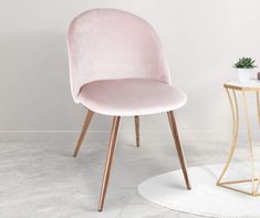 a pink chair sitting next to a table with a potted plant on top of it