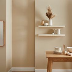 two white shelves with dishes and vases on them in a neutral living room setting