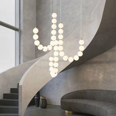 a modern chandelier hangs from the ceiling next to a curved staircase with circular lights