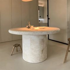 a white table sitting in the middle of a room next to two stools and a mirror