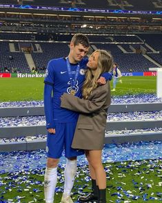 a man and woman standing next to each other on a field with confetti