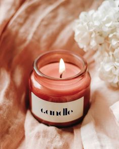 a pink candle sitting on top of a bed next to white hydrangea flowers