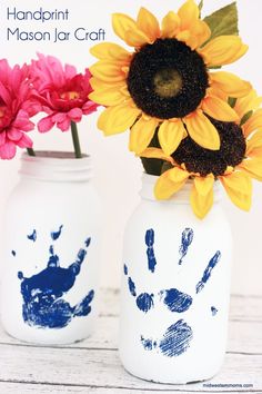 two painted mason jars with sunflowers and hand prints on them, sitting on a table