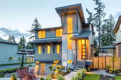 a house that is lit up at night with lights on the windows and landscaping around it