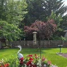 a bird statue sitting in the middle of a garden