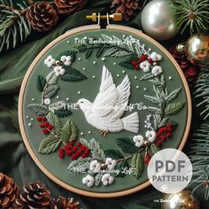 a cross stitch pattern with a white dove and holly wreath