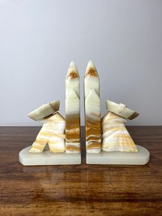 two white and brown sculptures sitting on top of a wooden table