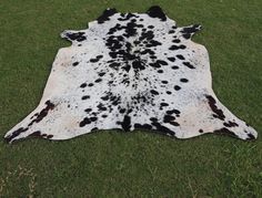 a black and white spotted cowhide rug on grass