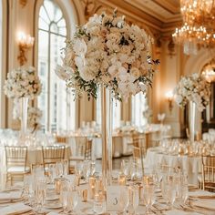 a tall vase filled with white flowers sitting on top of a table covered in candles