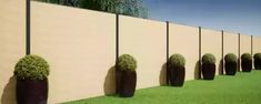 a row of planters sitting on top of a grass covered field next to a wall