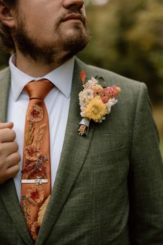 a man wearing a suit and tie with flowers on it's lapel flower