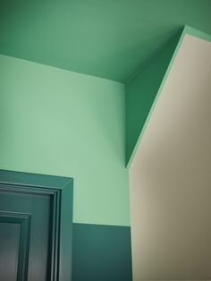 the corner of a room painted green and white with a door in front of it