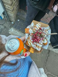 a person holding up a can of soda and some kind of food on the street