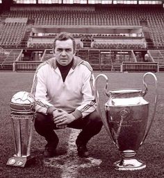 a man kneeling down next to two soccer trophies