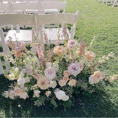 an arrangement of flowers is sitting in the grass at a wedding ceremony with white chairs