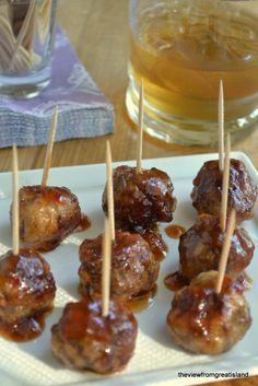 small meatballs with toothpicks on a plate next to a glass of beer