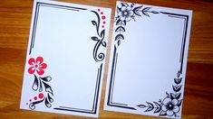 two white cards with black and red designs on them sitting on a wooden table next to each other