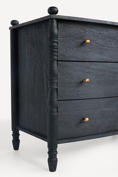 a black wooden dresser with gold knobs on the top and bottom drawers, against a white background