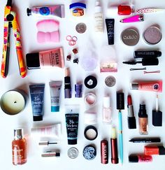 an assortment of cosmetics and makeup products arranged on a white surface, top down view