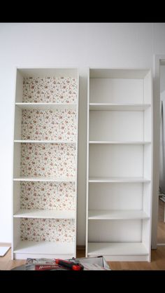 an empty white bookcase sitting on top of a hard wood floor next to a wall