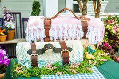 two pieces of luggage sitting on top of a green table covered in flowers and grass