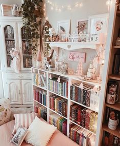 a room with bookshelves, pillows and pictures on the wall above it that are decorated with christmas lights