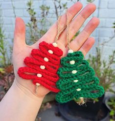 two crocheted christmas tree ornaments are held in someone's hand