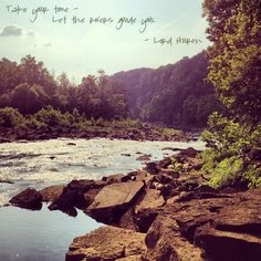 there is a river that has rocks in the water and trees on both sides with an inspirational quote above it