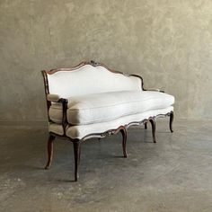 a white couch sitting on top of a wooden frame in front of a gray wall